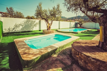 Una piscina al aire libre, sillones reclinables de piscina
