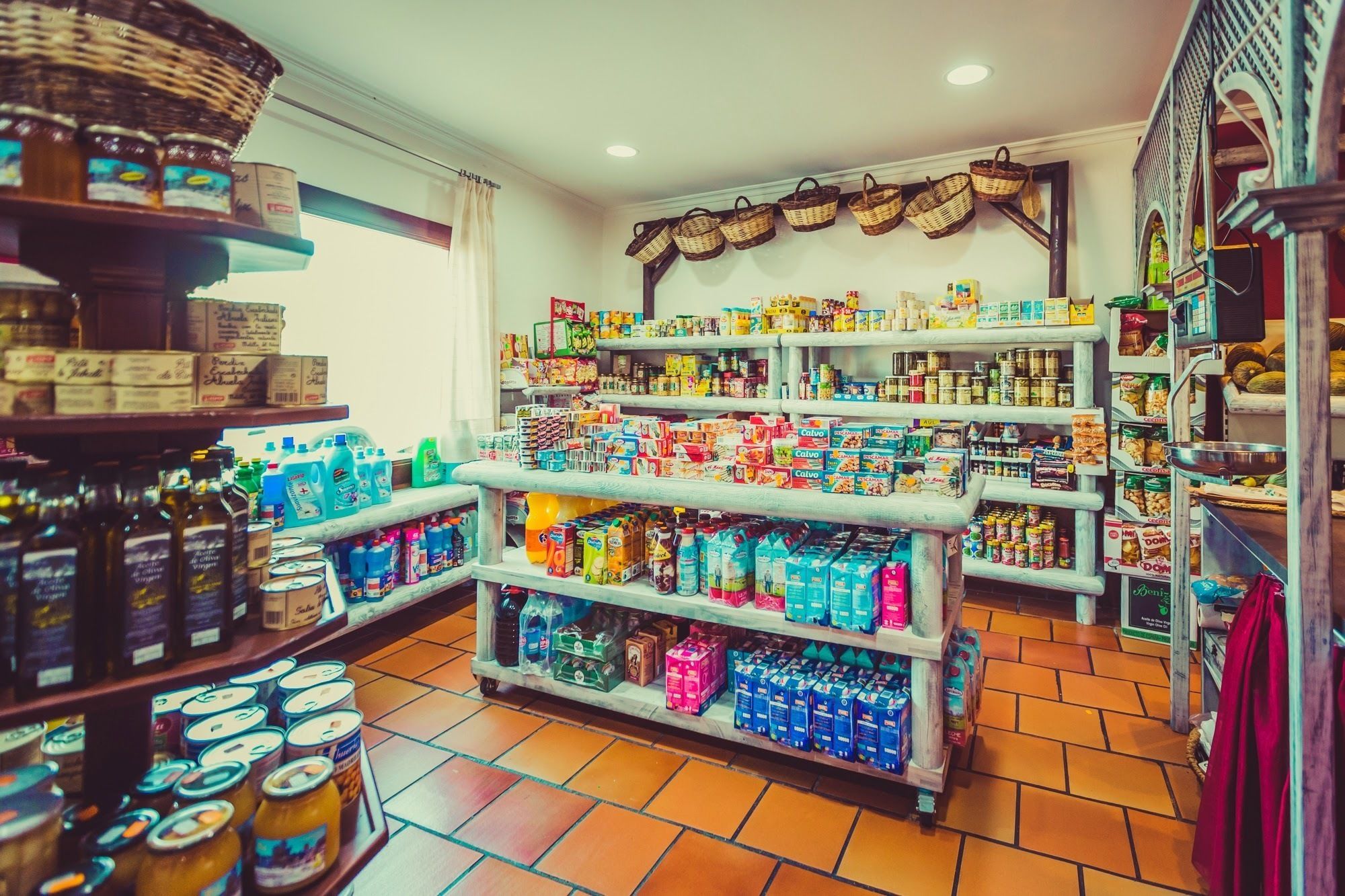 Une épicerie dont les rayons sont remplis de divers produits, notamment des conserves, des boissons et des articles ménagers.