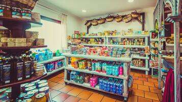 Une épicerie dont les rayons sont remplis de divers produits, notamment des conserves, des boissons et des articles ménagers.