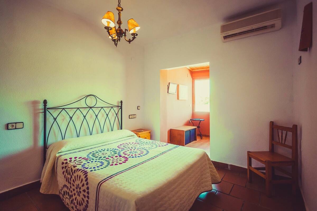Een slaapkamer met een bed, een stoel, een bureau en een kroonluchter.