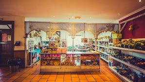 Un supermercado con suelos de baldosas, estanterías repletas de productos variados y una zona de exhibición central.