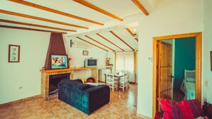 Una sala de estar con chimenea, un sofá, un televisor y un comedor con sillas y una mesa.