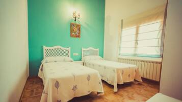 A room with two beds, a radiator, and a window with blinds.