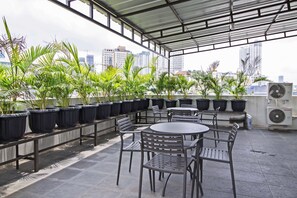 Una terraza en la azotea con plantas en macetas, mobiliario exterior y vistas al perfil urbano.