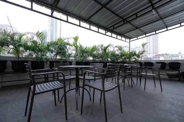 Une terrasse sur le toit, dotée d’un espace extérieur aménagé avec des plantes en pot, offrant une vue sur le paysage urbain.