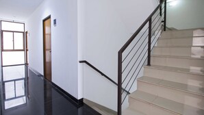 Un interior moderno con una escalera, una puerta y un ventanal que da a un espacio luminoso.