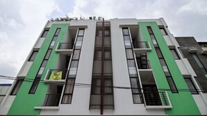 Un edificio moderno con fachada simétrica, que presenta un elemento vertical central y balcones en cada piso.