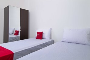 Une chambre d’hôtel avec deux lits, une armoire et un miroir.