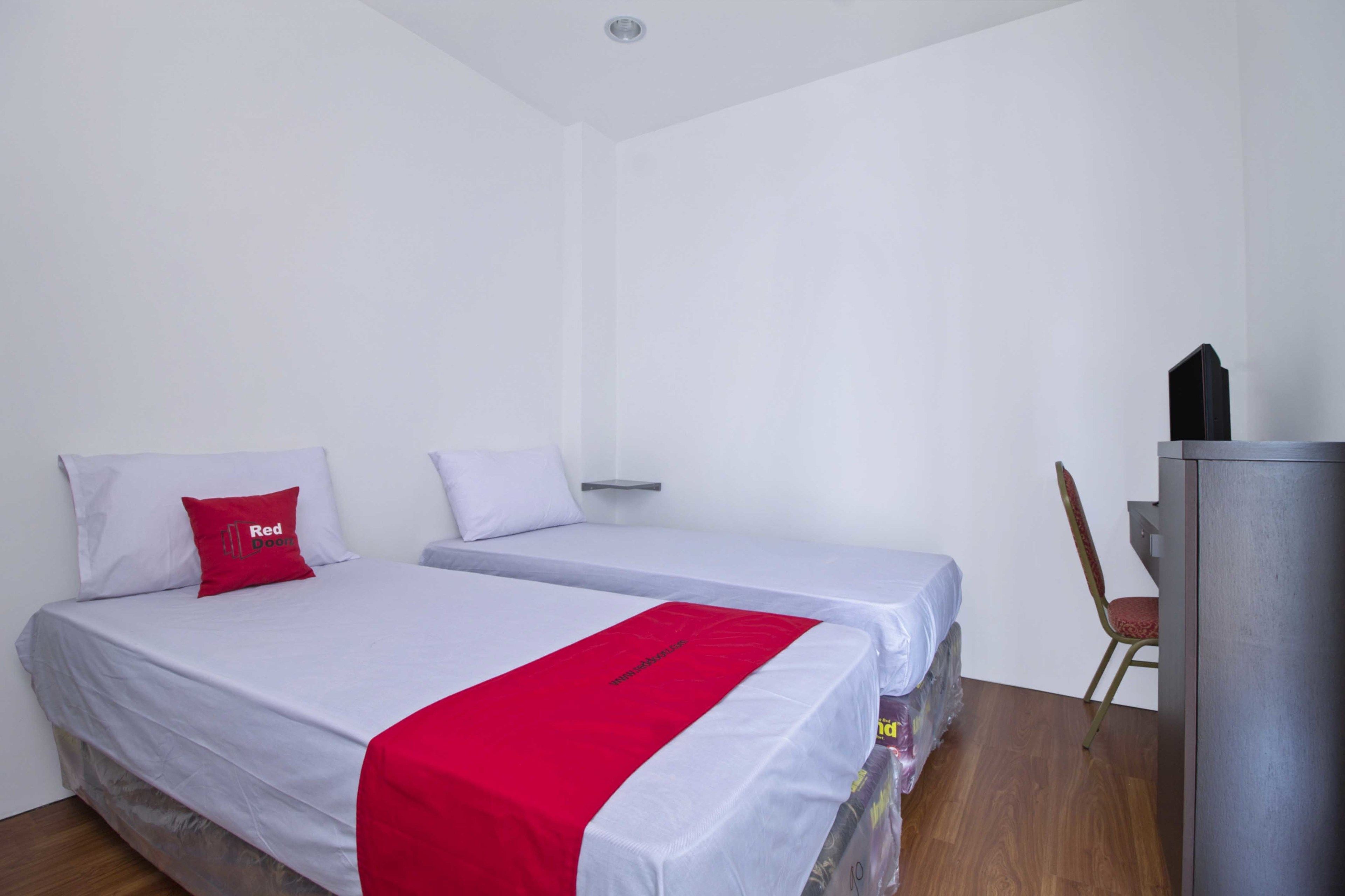 A hotel room with two single beds, a desk, and a chair.