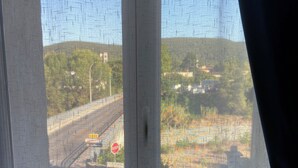 Vista a través de una ventana con un diseño de cuadrícula, una señal de stop y una carretera con vehículos.