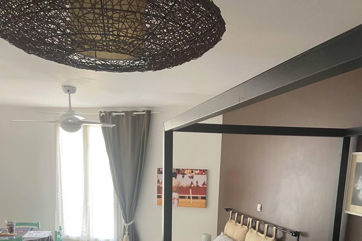 A room with two beds, a dining table, and a ceiling fan.