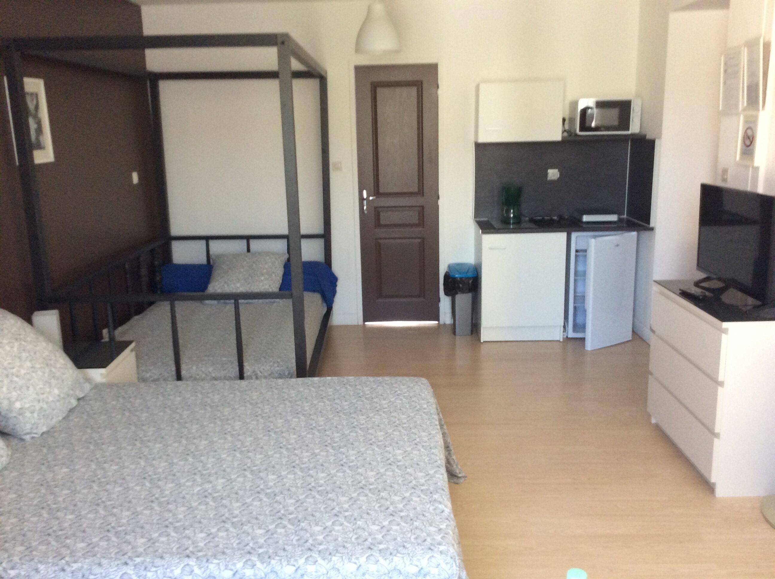 A compact room with bunk beds, a kitchenette, and a TV.