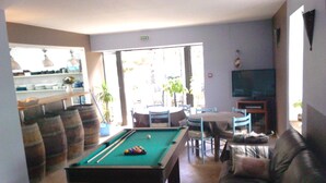Una sala de estar con mesa de billar, sofá, televisión y comedor.