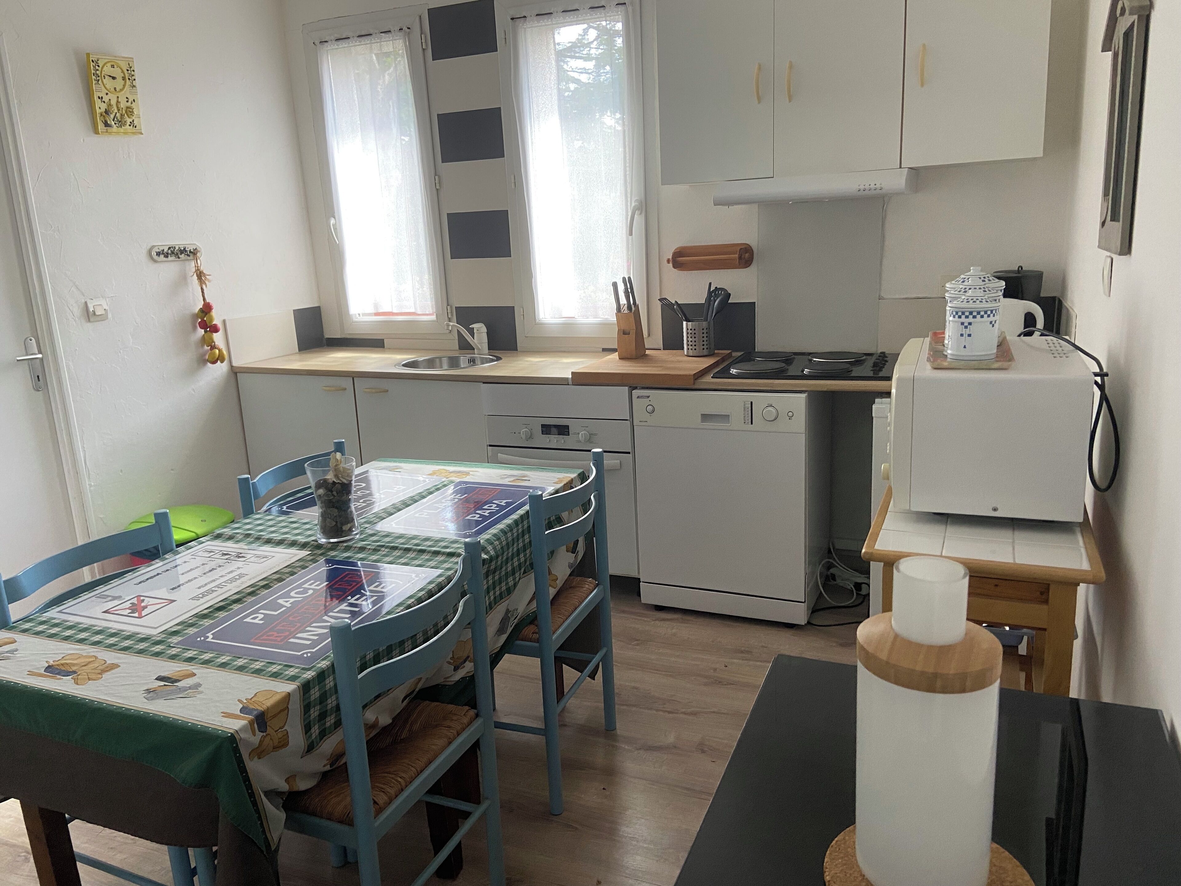 A compact kitchen with a dining area, featuring a sink, stove, and dishwasher.