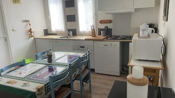 A compact kitchen with a dining area, featuring a sink, stove, and dishwasher.