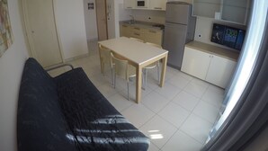 A compact kitchen with a dining area, a sofa, and a television. - Residence Zenith (Caorle)