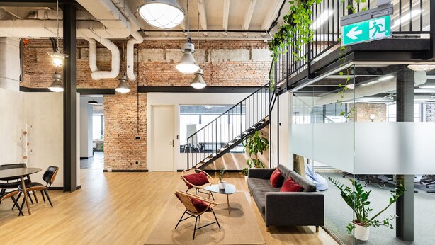 An open-plan office space with a staircase, wooden flooring, and modern furniture. - Wine Apartments (Kraków)