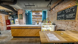 A cozy cafe with a brick wall, wooden counter, and a menu board. - Wine Apartments (Kraków)