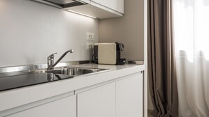 A modern kitchen with white cabinetry, stainless steel appliances, and a built-in oven. - MYSWEETPLACE - Largo Europa Apartments (Padova)