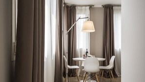 A modern hotel room with a round dining table, white chairs, a floor lamp, and large windows with curtains. - MYSWEETPLACE - Largo Europa Apartments (Padova)