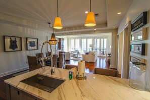 A modern kitchen with a marble countertop, pendant lighting, and a view to the dining area. - Rosemary Beach Rentals by Counts-Oakes (Panama City Beach)