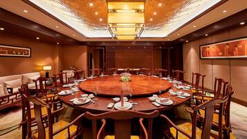 A conference room with a round table, wooden chairs, and a chandelier.