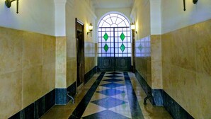 A hallway with a geometric patterned floor, white walls, and two wall-mounted lights. - Guest House Cavour 278 (Rome)