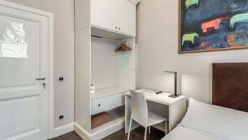 A bedroom with a bed, a desk with a chair, a wardrobe, and a painting on the wall.