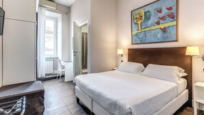 A hotel room with a large bed, a desk, a chair, and a window with curtains. - Guest House Cavour 278 (Rome)