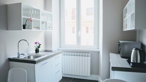 A modern kitchen with white cabinetry, a built-in sink, and a window providing natural light. - Guest House Cavour 278 (Rome)