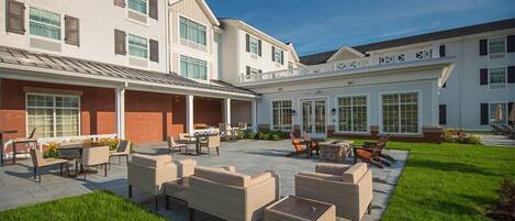 A spacious outdoor patio with multiple seating areas, a covered section, and a well-maintained lawn.