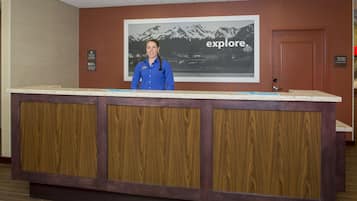 A reception desk with a wooden panel design, a framed picture of mountains, and a sign that says "explore."