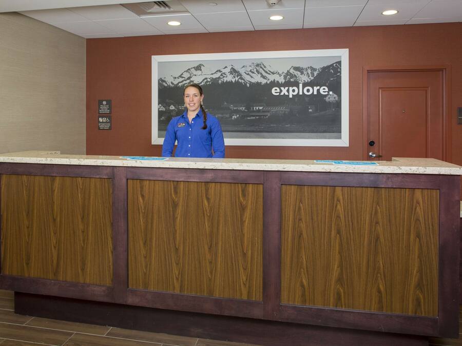 A reception desk with a wooden panel design, a framed picture of mountains, and a sign that says "explore."