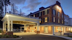 A hotel with a covered entrance, outdoor seating, and a clear sign indicating a 12-foot clearance.