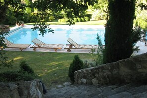 Una piscina con sillones de descanso y un muro de piedra.
