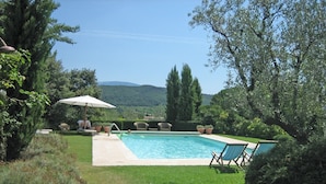 A swimming pool with lounge chairs and an umbrella, surrounded by greenery and hills in the background. - Mansion in Vaison-la-Romaine with Private Pool (Vaison la Romaine)