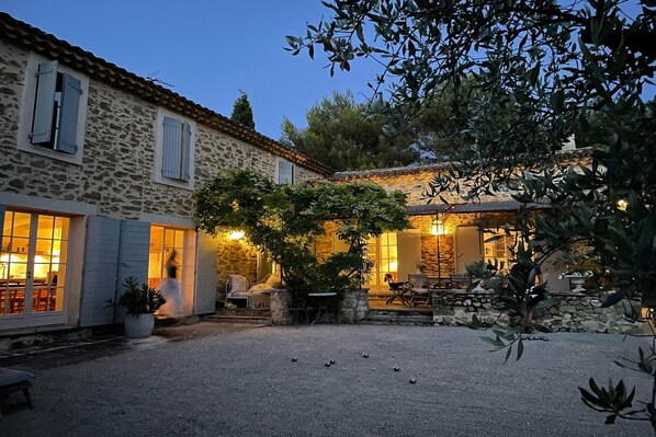 A stone building with a courtyard, outdoor seating, and a well-lit interior.