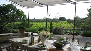 An outdoor dining area with a table set for two, surrounded by a vineyard view.