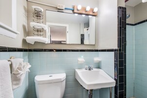 Un baño con inodoro, lavamanos y espejo con iluminación.