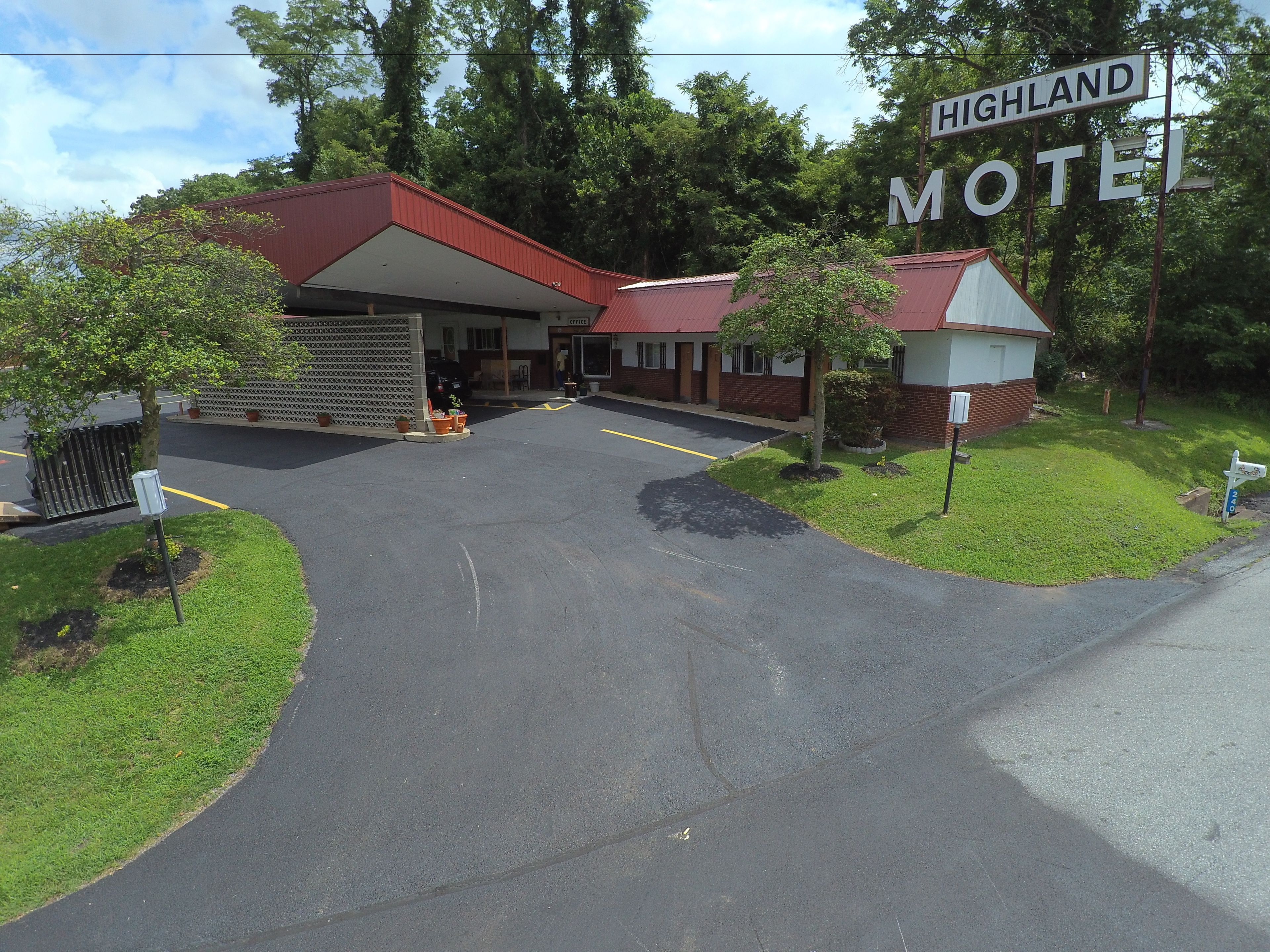 A motel with a red roof and a sign that reads "Highland Motel."