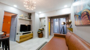 A modern living room with a TV, sofa, and decorative items. - Once21 Apartments (Guadalajara)