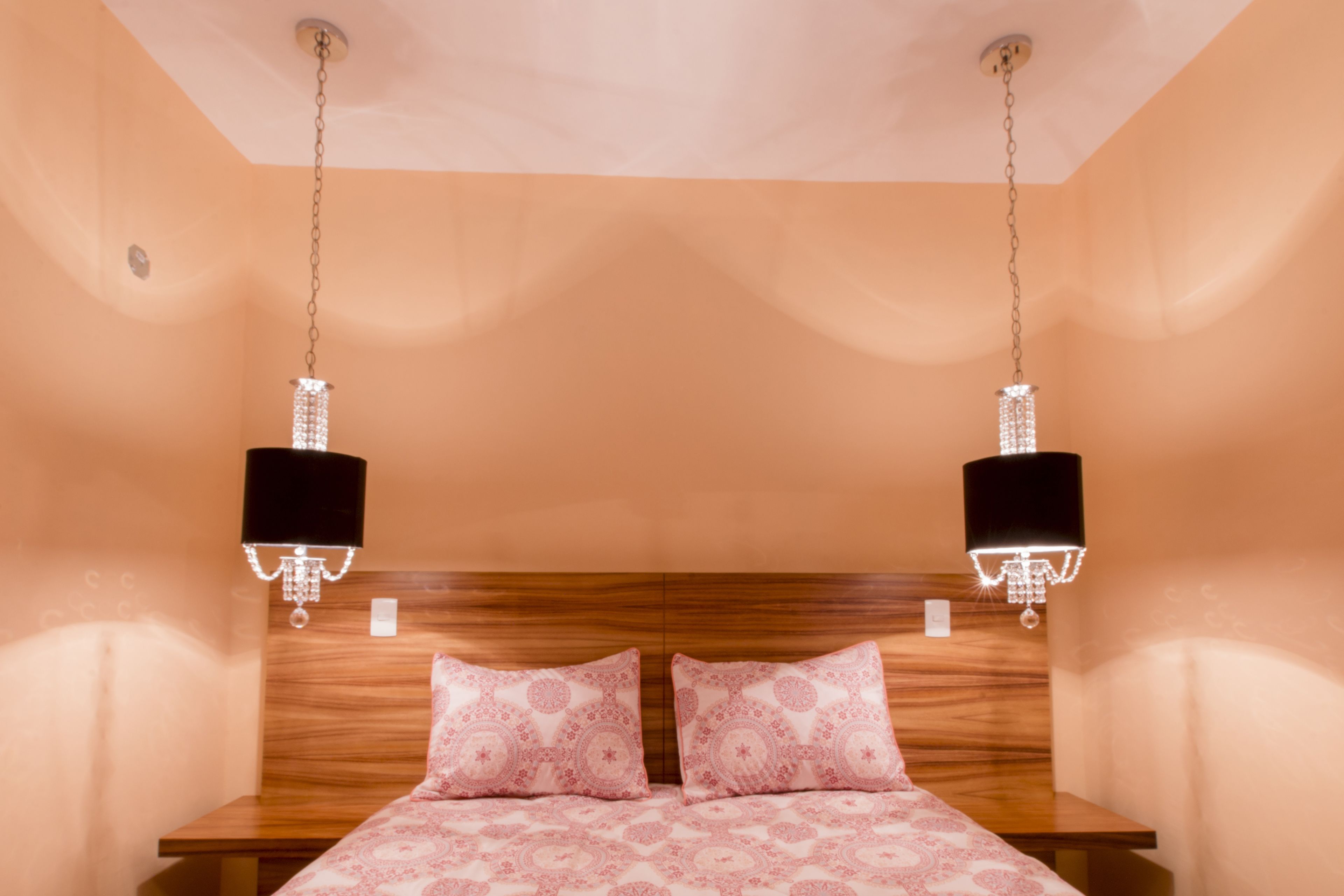 A bedroom with a wooden headboard, two bedside lamps, and a patterned bedspread.