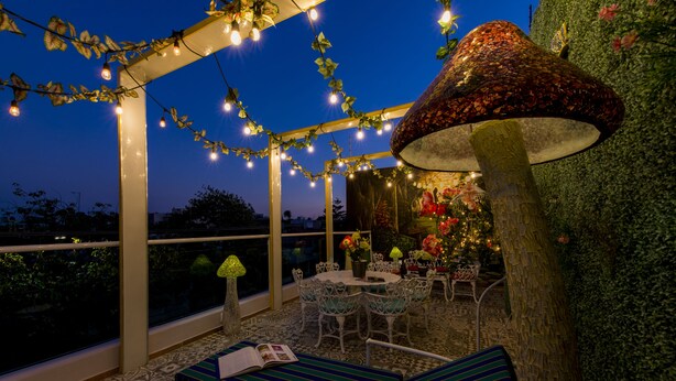 An outdoor patio with string lights, a table with chairs, and a decorative mushroom lamp. - Once21 Apartments (Guadalajara)