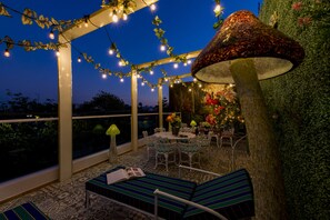An outdoor patio with string lights, a table with chairs, and a decorative mushroom lamp. - Once21 Apartments (Guadalajara)