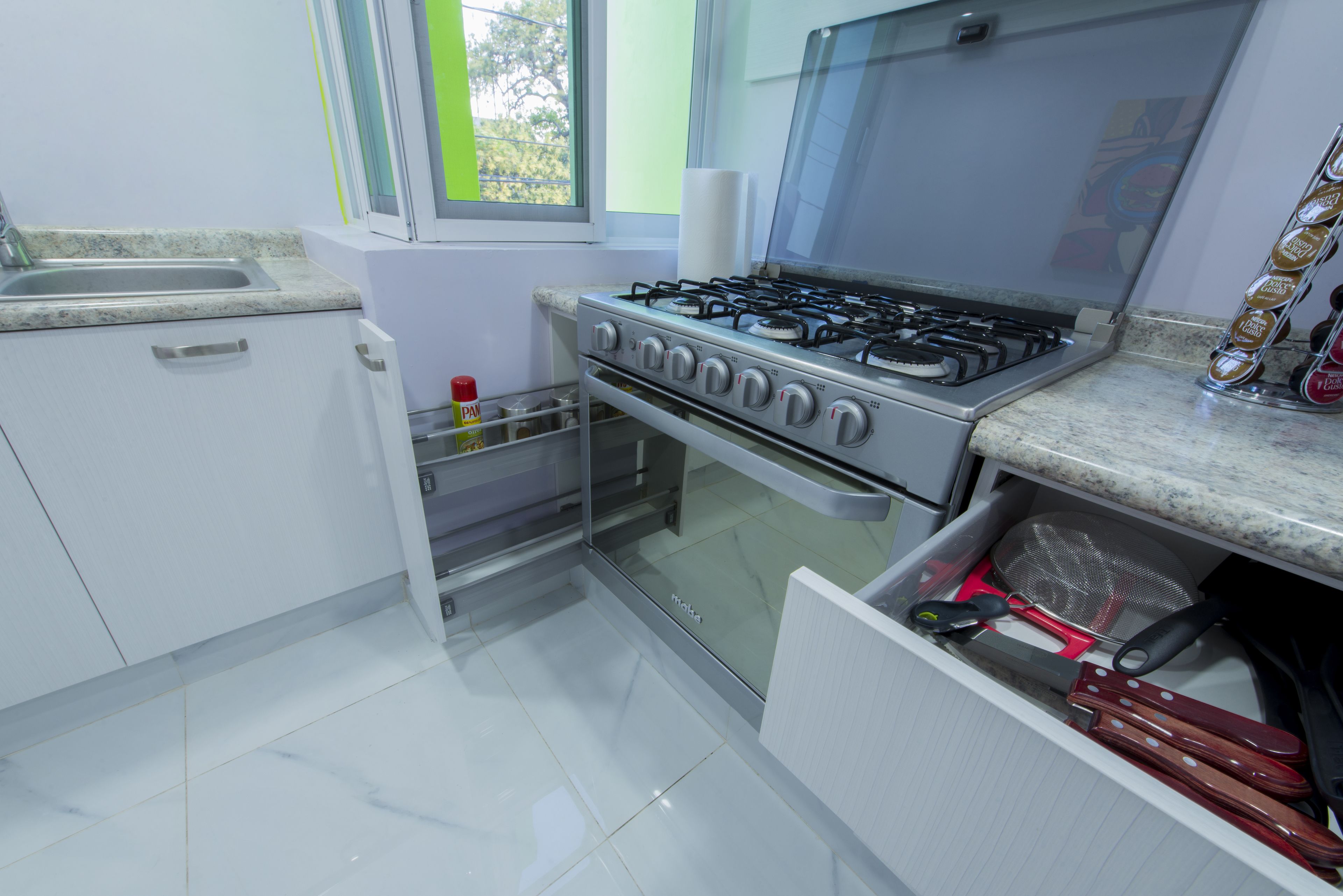 A kitchen with a gas stove, a sink, and a window.