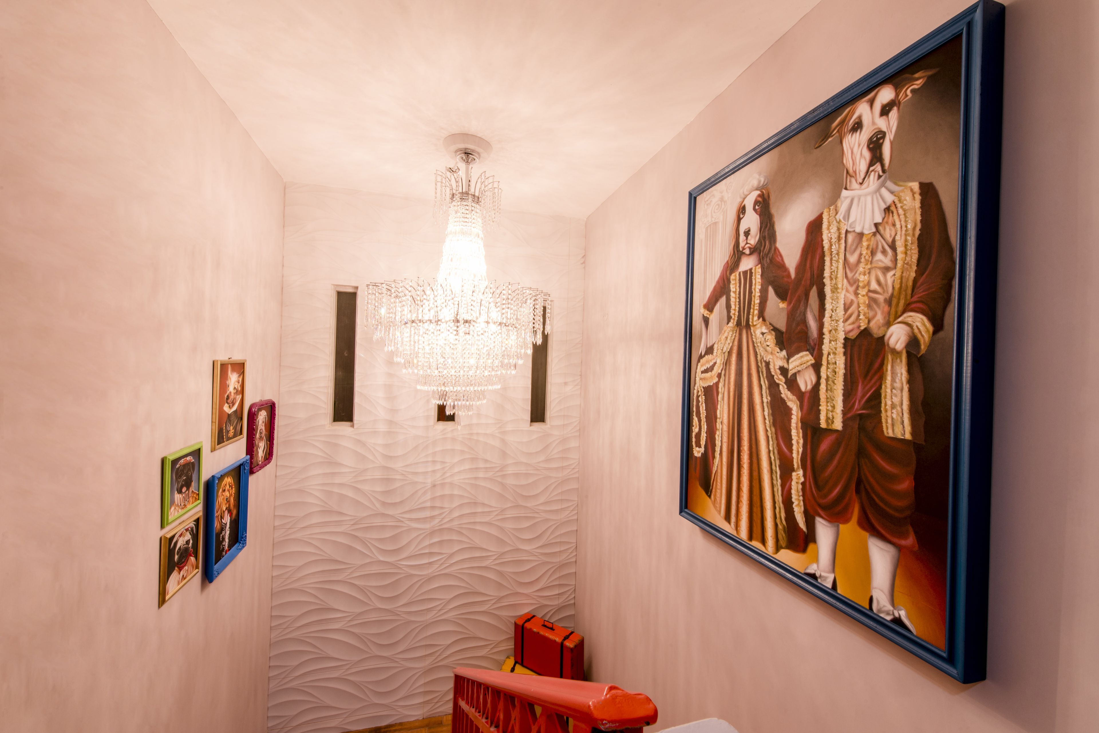 A hallway with a textured wall, a chandelier, framed artwork, and a staircase.