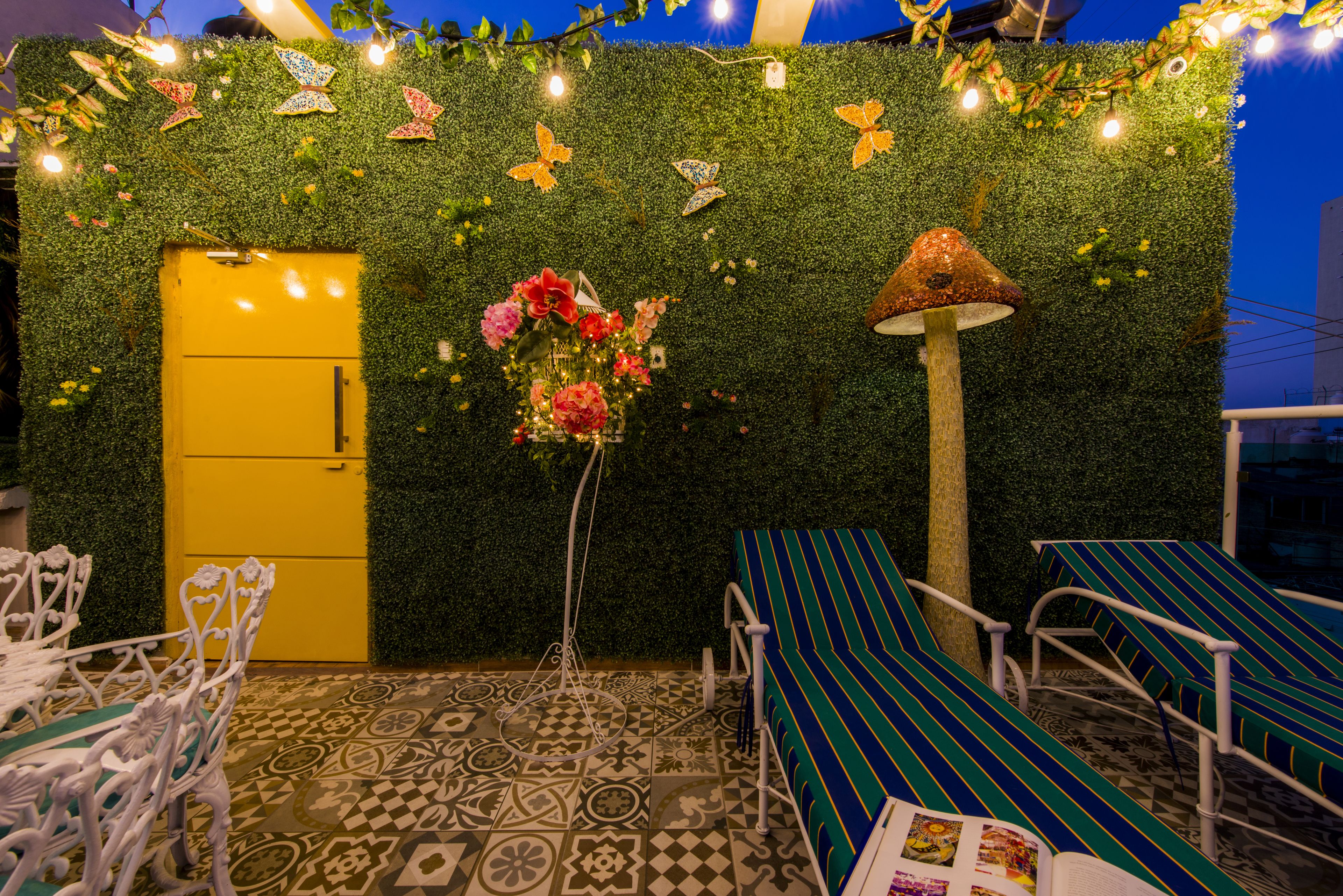 Un patio con suelo estampado, una puerta amarilla y sillones a rayas.