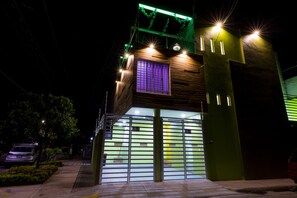 A modern building with a green facade, a purple window, and a gated entrance. - Once21 Apartments (Guadalajara)
