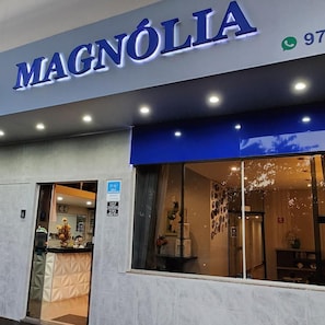 A storefront with the name 'MAGNÓLIA' illuminated above the entrance.