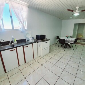 A kitchen with a dining area, a ceiling fan, and a window with curtains. - Hotel Magnolia (Sao Joao da Boa Vista)